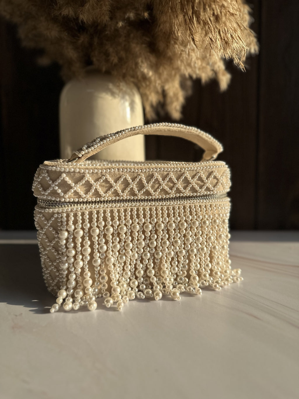Handheld view of the Adira bag showing its compact proportions next to evening wear.