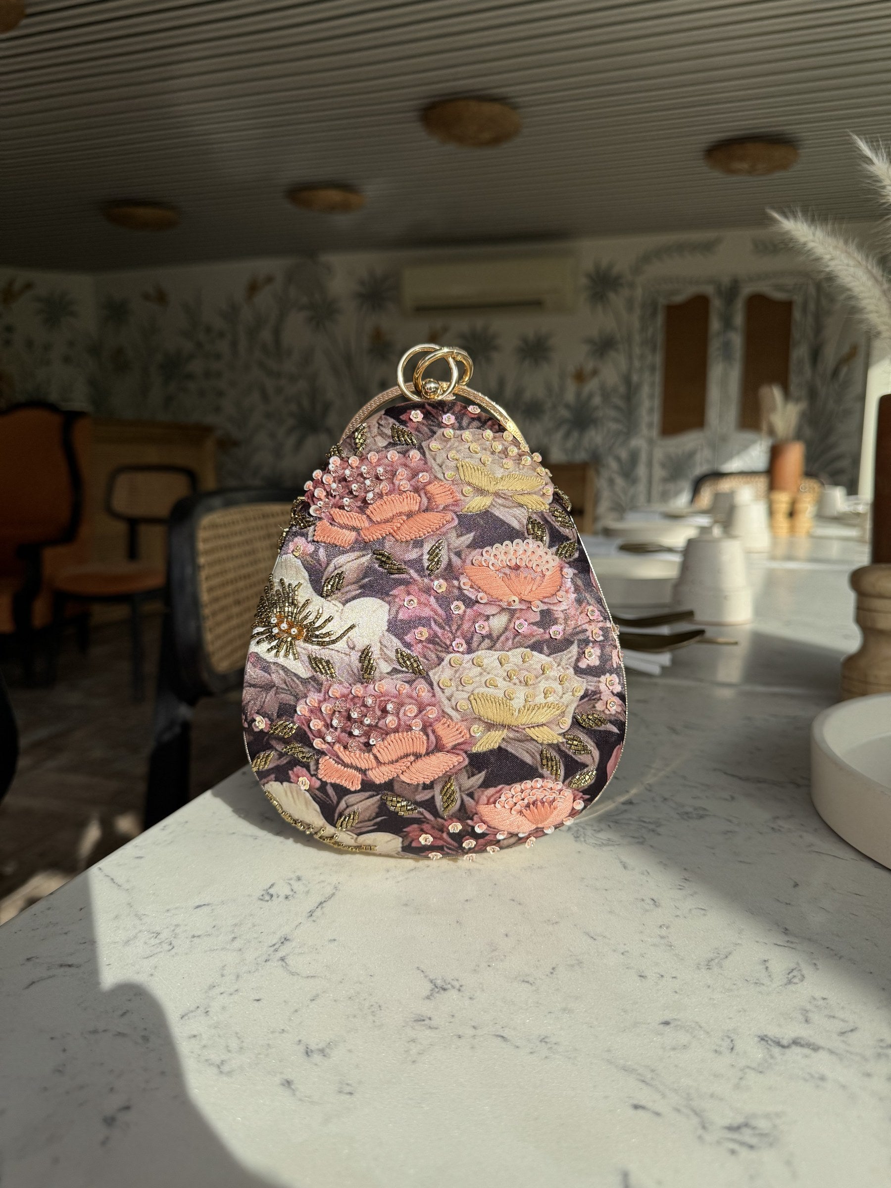 Lifestyle flat lay of the clutch next to cosmetics and jewelry.