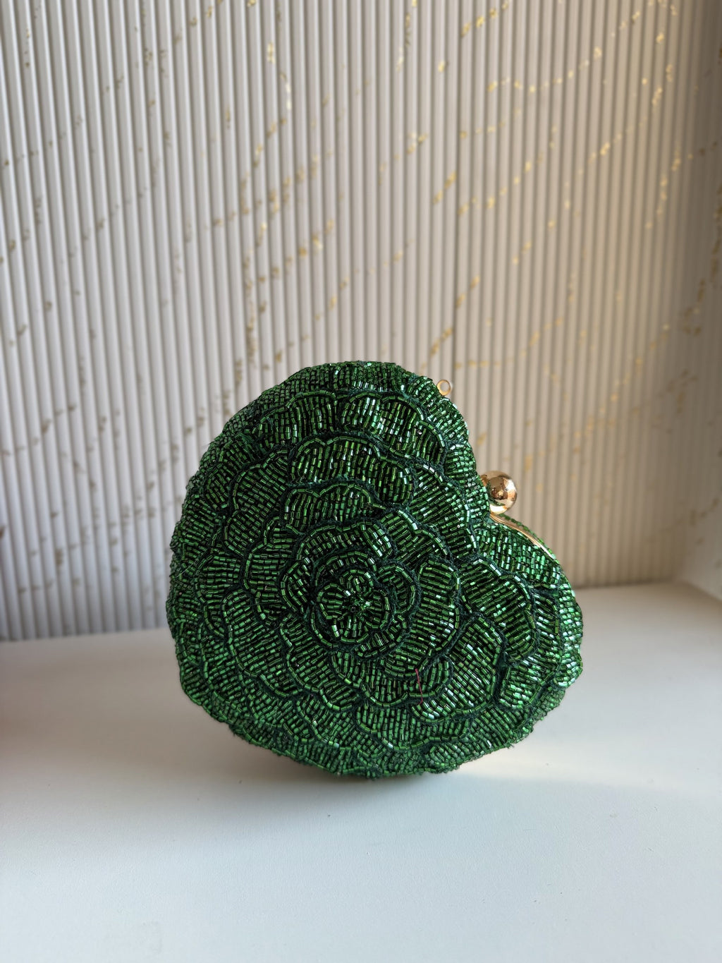 The Amour heart bag held by a model, illustrating its compact scale relative to evening wear.
