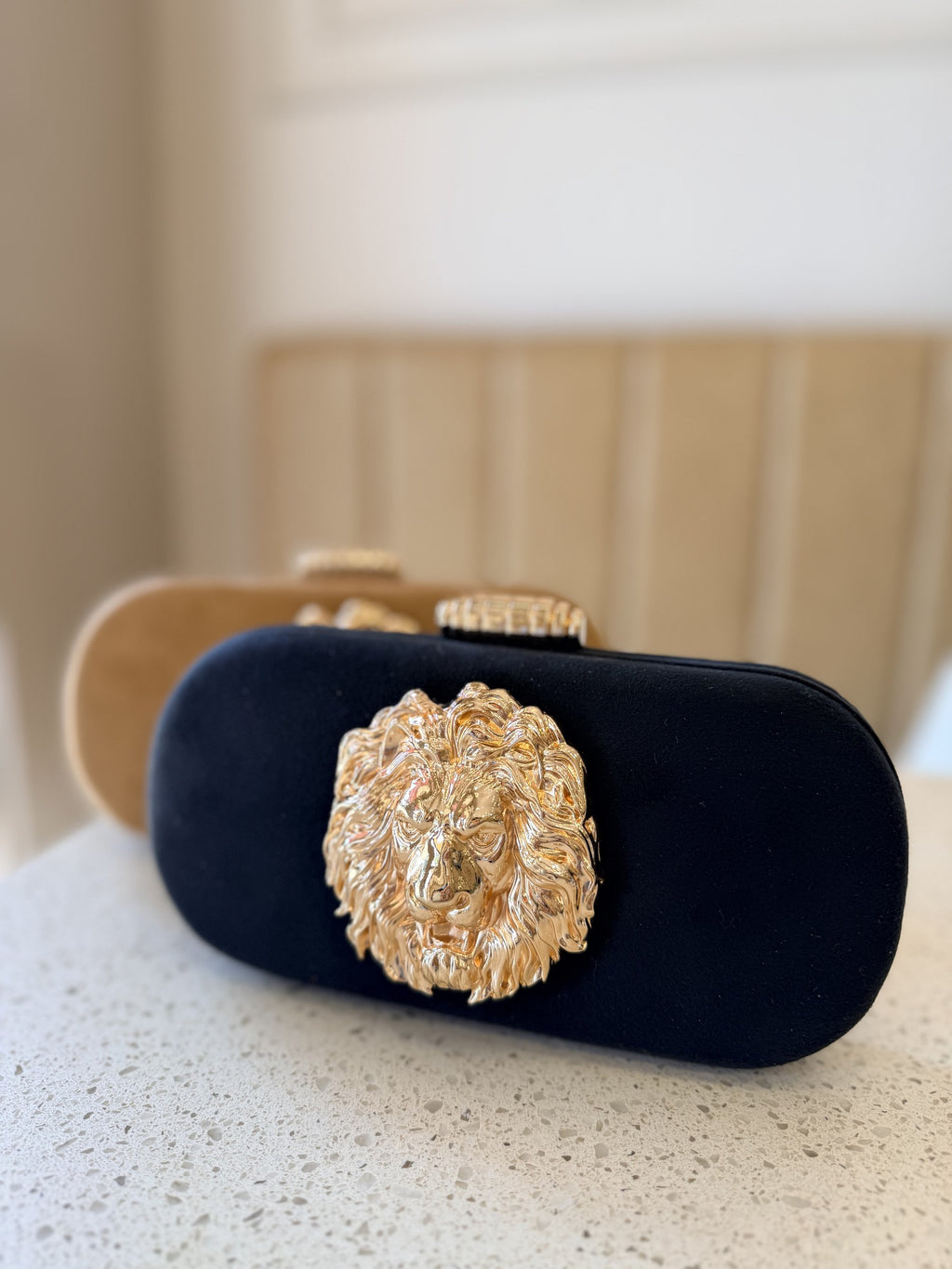 Aurelia clutch displaying its radiant gold metallic finish and gold-tone sling chain.