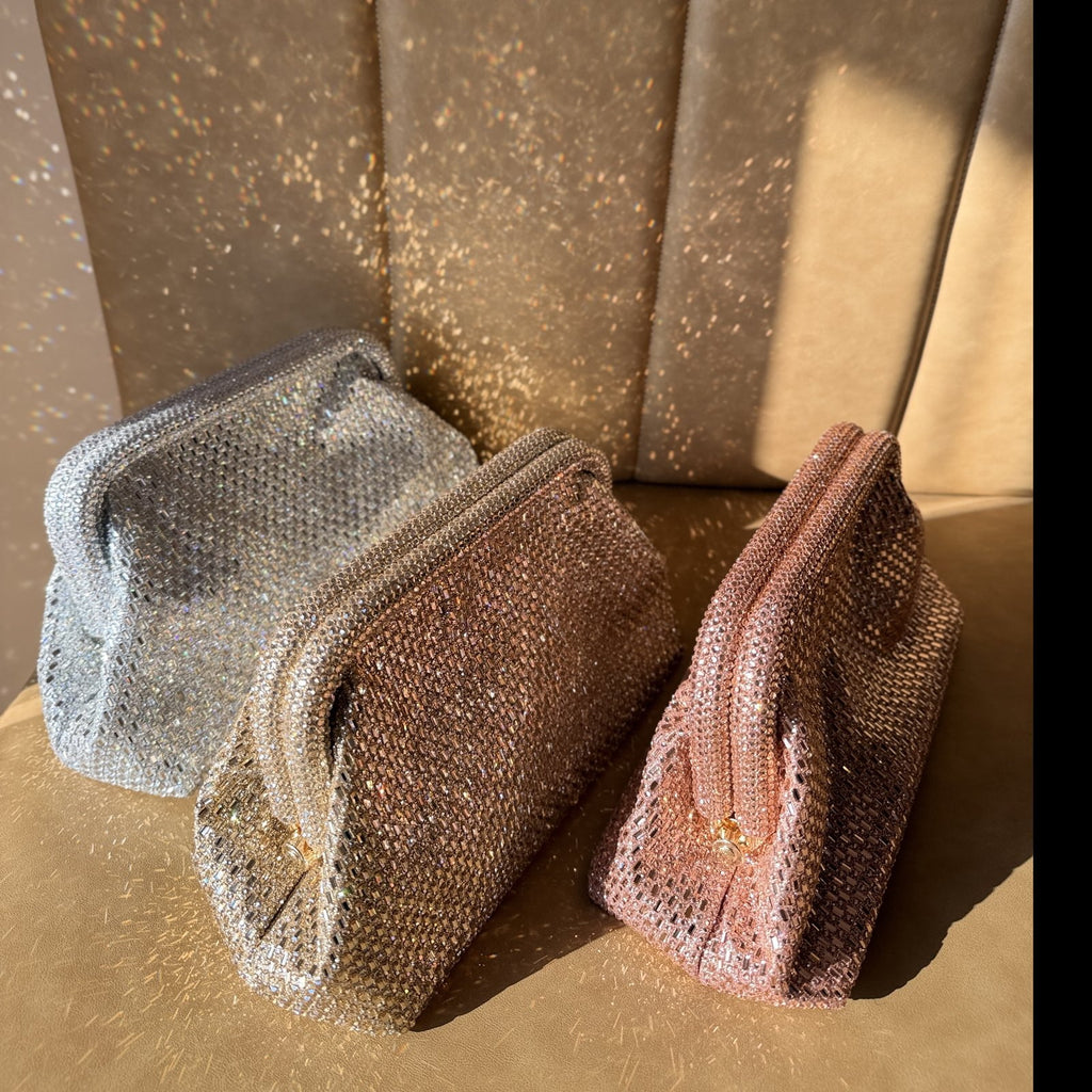The Aurelle clutch held by its gold chain, showcasing its shoulder drape option.