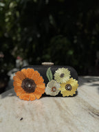 Bloom Box floral embroidered clutch displaying its multicolored flower stitching and gold-tone sling chain.