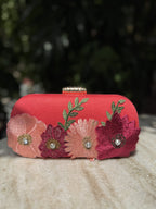 Angled view of the Bloom Box clutch showing the secure gold border clasp lock.