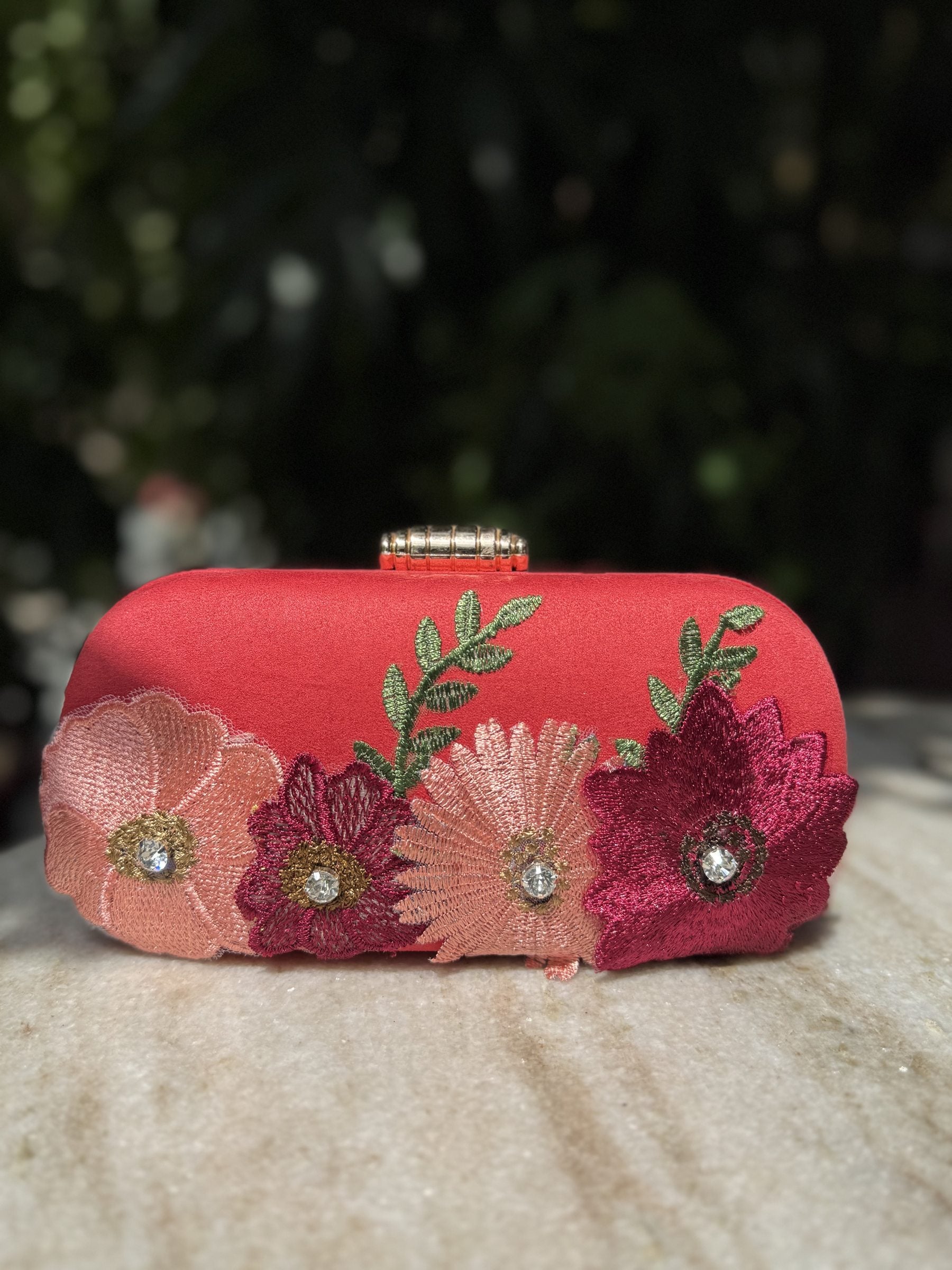 Angled view of the Bloom Box clutch showing the secure gold border clasp lock.