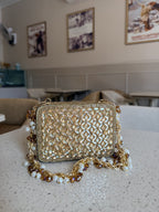 Side angle of the mini bag showing its structured fabric borders and gold metal loops.