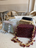 The Champagne Crush mini bag held by its short embellished chain, showcasing wristlet styling.