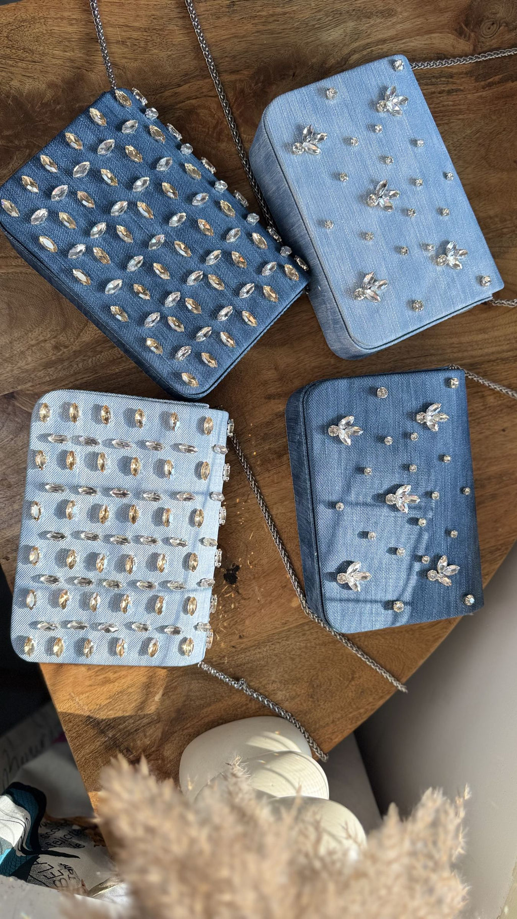 Flat-lay image of the denim sling bag shown with sunglasses, keys, and an iPhone Pro Max to illustrate size.