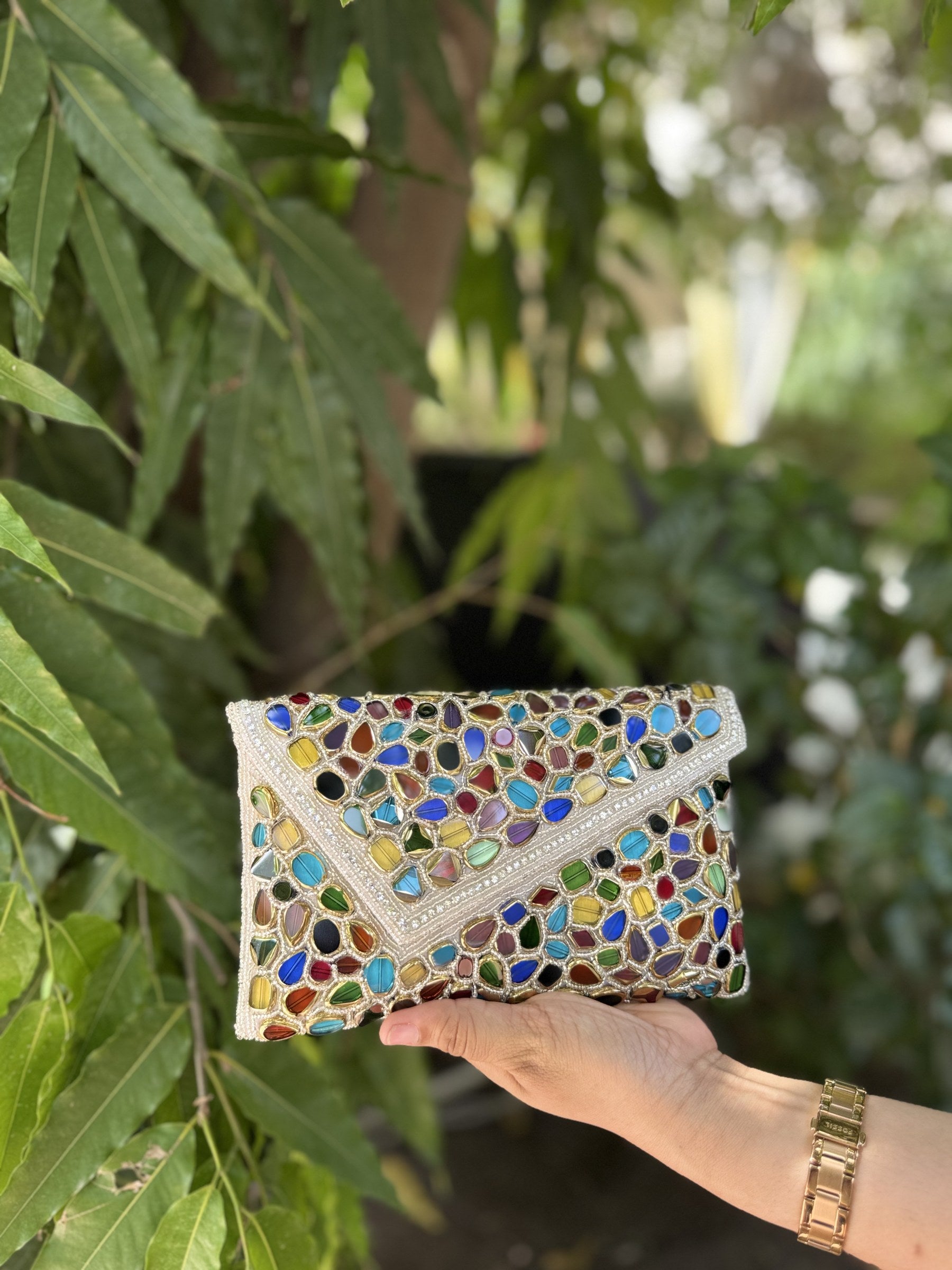 Gemzy hand-embellished flap bag displaying its vibrant multicolored gemstone pattern and gold-tone sling chain.