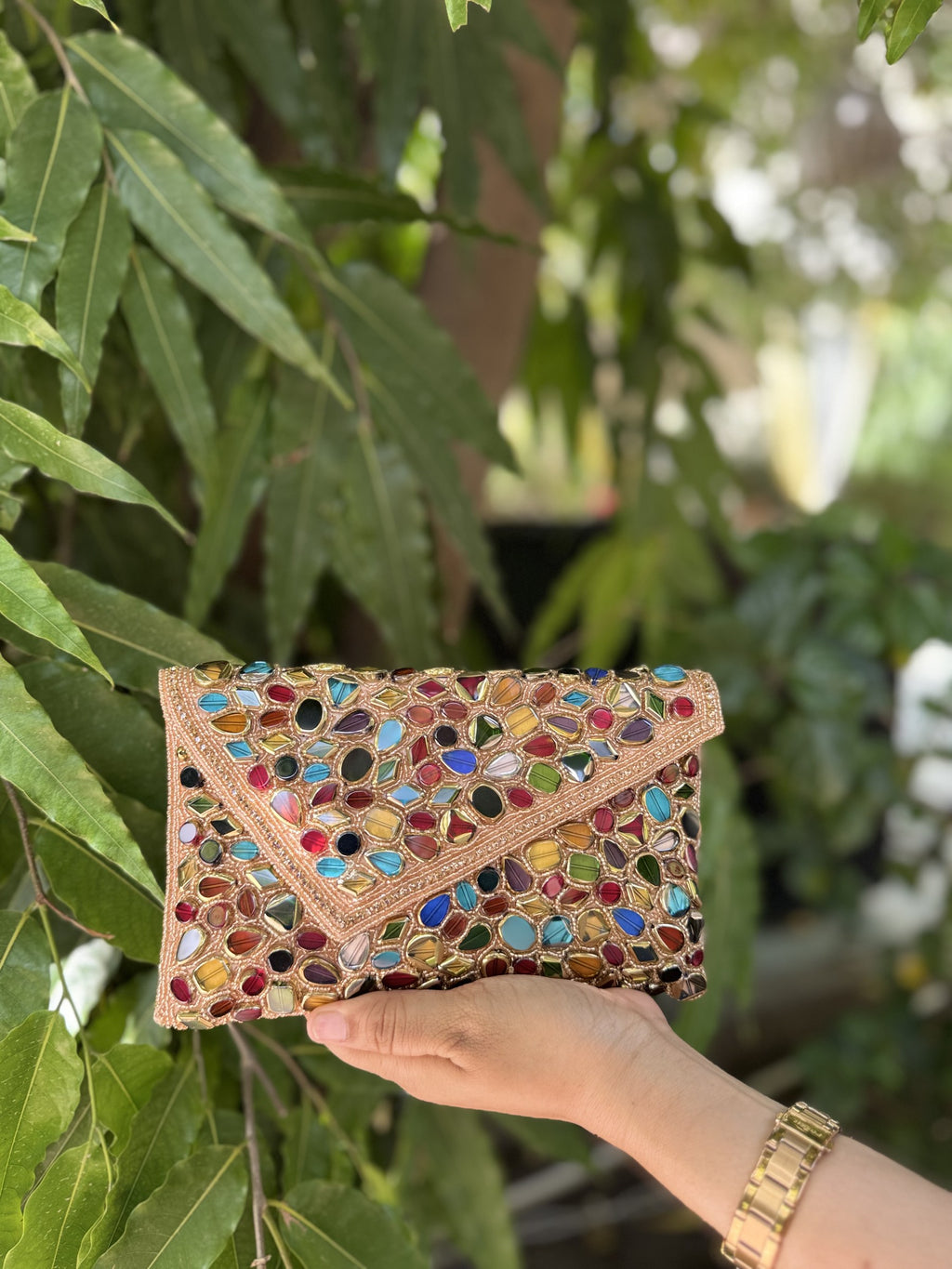 Angled view of the Gemzy clutch bag styled handheld with its gold-tone chain draped elegantly.