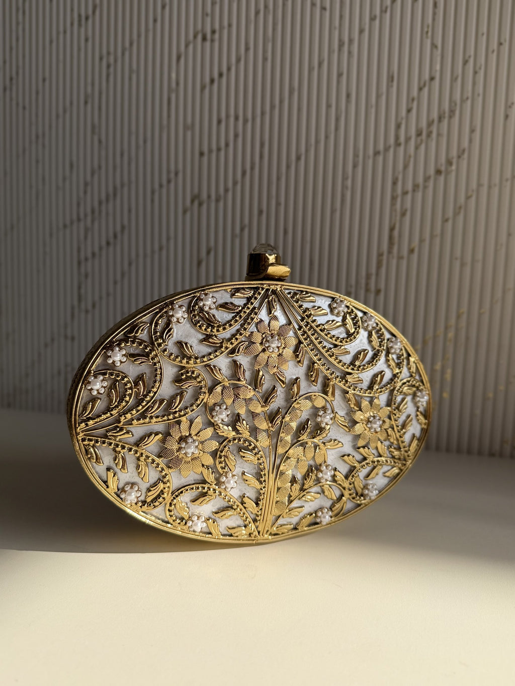 Gilded Muse rectangular brass clutch showing its hand-sculpted gold surface and metal clasp closure.