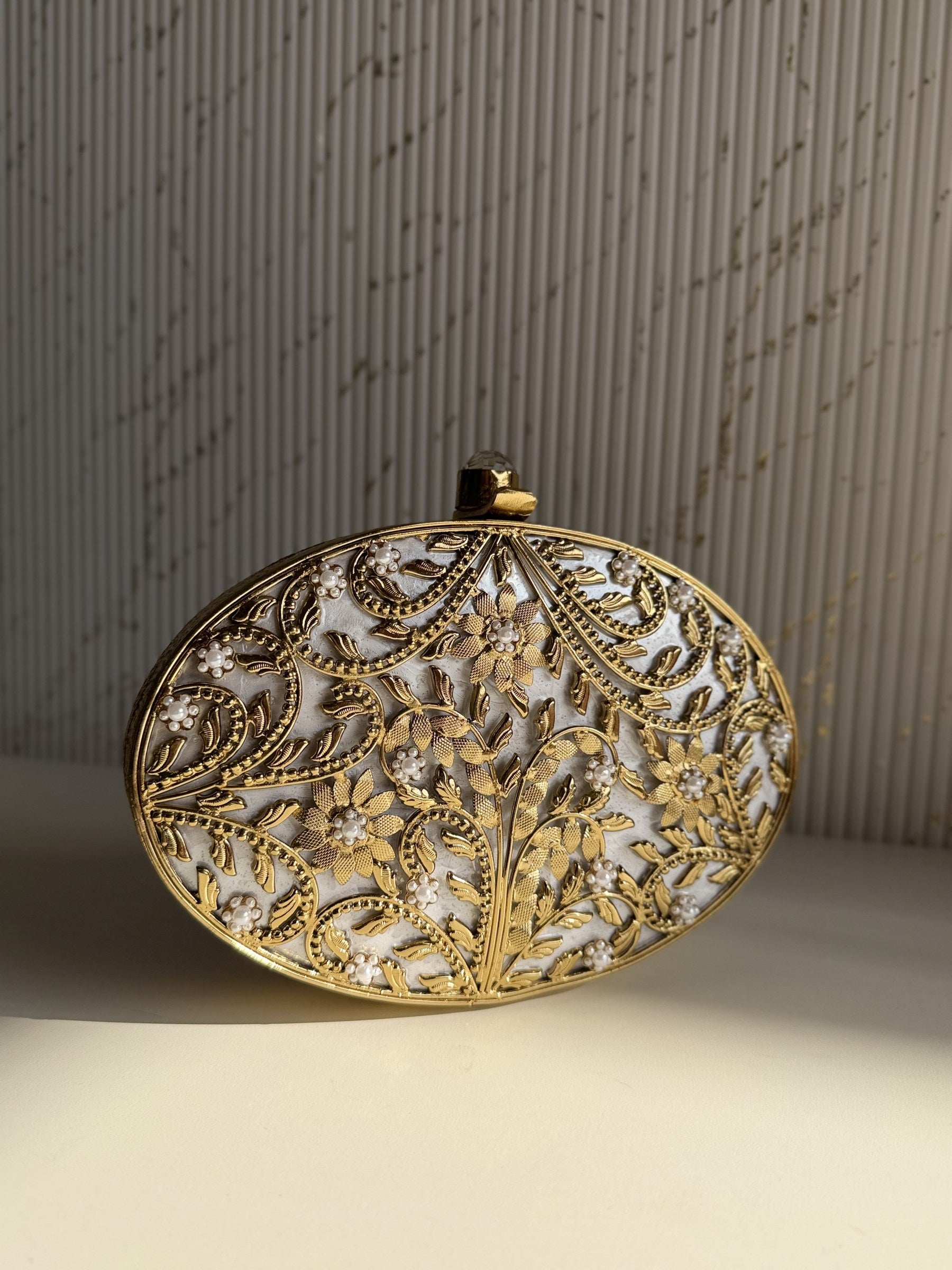 Gilded Muse rectangular brass clutch showing its hand-sculpted gold surface and metal clasp closure.