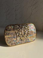 Front view of the Gilded Muse oval brass clutch, highlighting its smooth curves and gold finish.