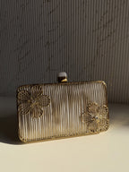 Side angle of the oval brass clutch showing its structured depth and hinge mechanism.