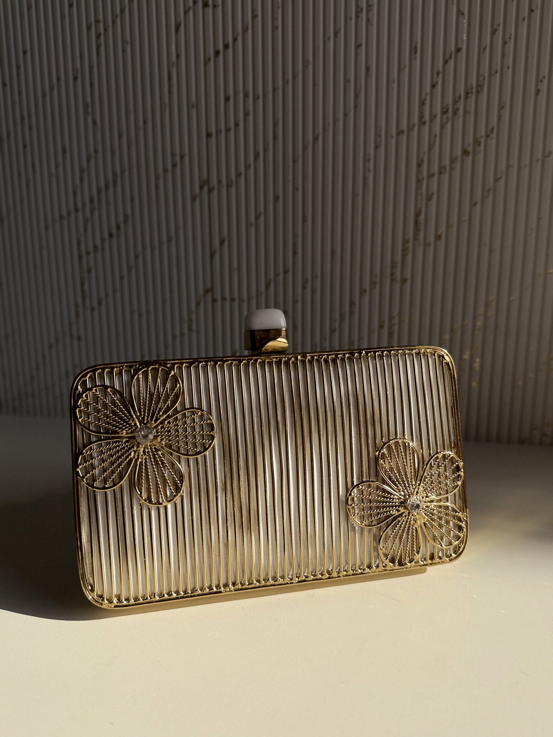 Side angle of the oval brass clutch showing its structured depth and hinge mechanism.