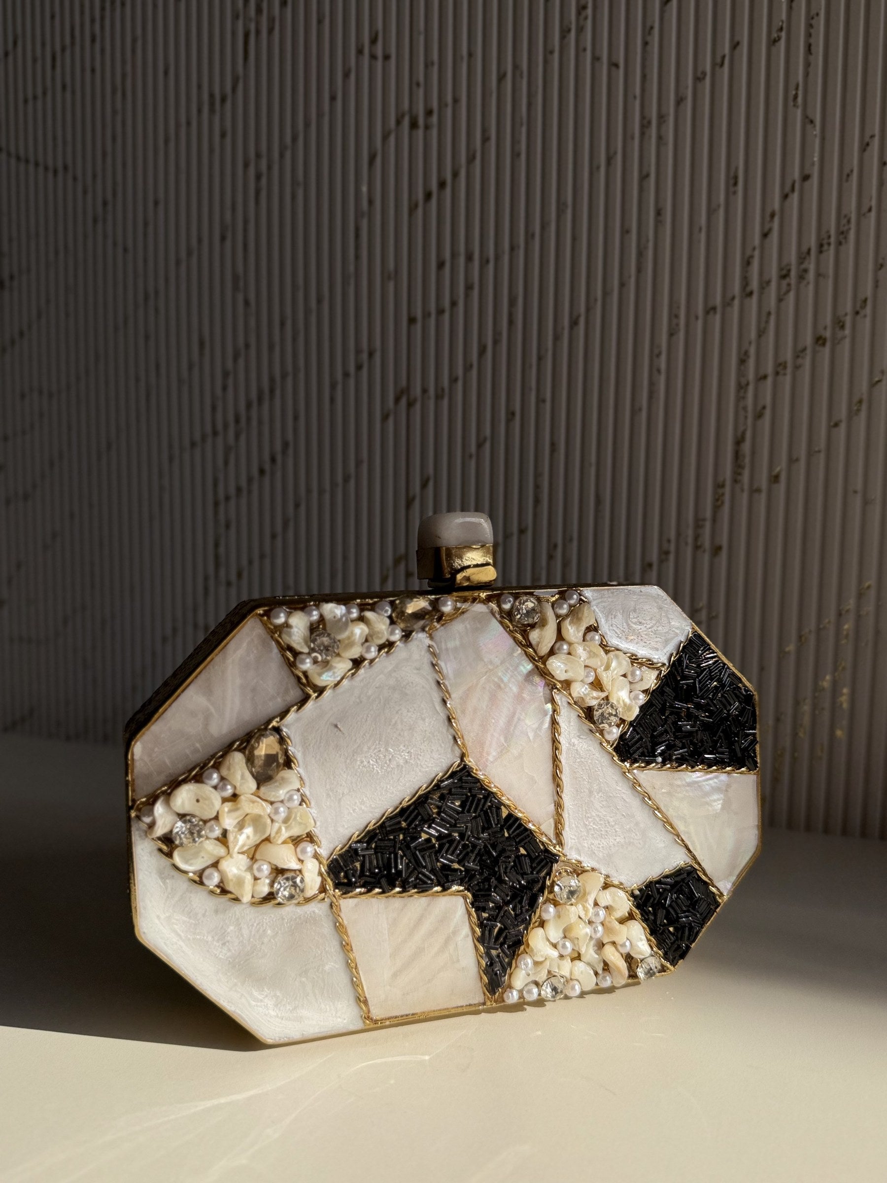 The Gilded Muse round brass clutch displaying its compact, circular silhouette and sculpted patterns.