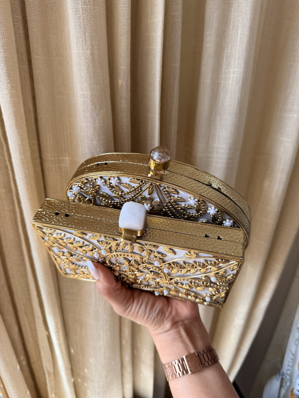 Open view of the round brass clutch showing the interior space for keys and cosmetics.