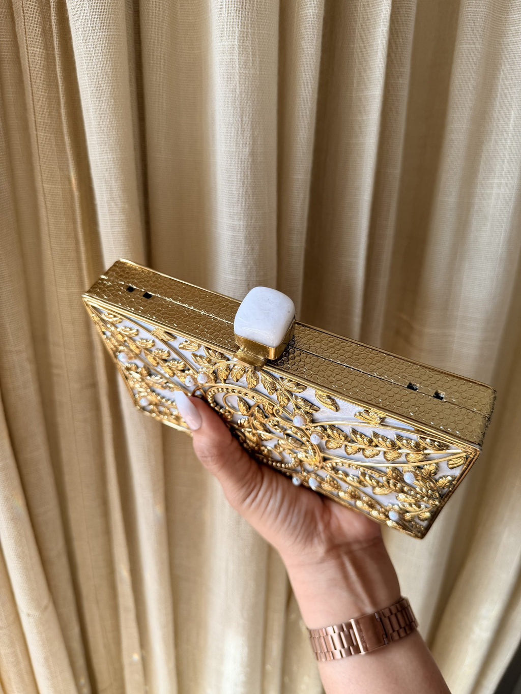 The Gilded Muse oval clutch styled with its shoulder-length chain draped over the shoulder.