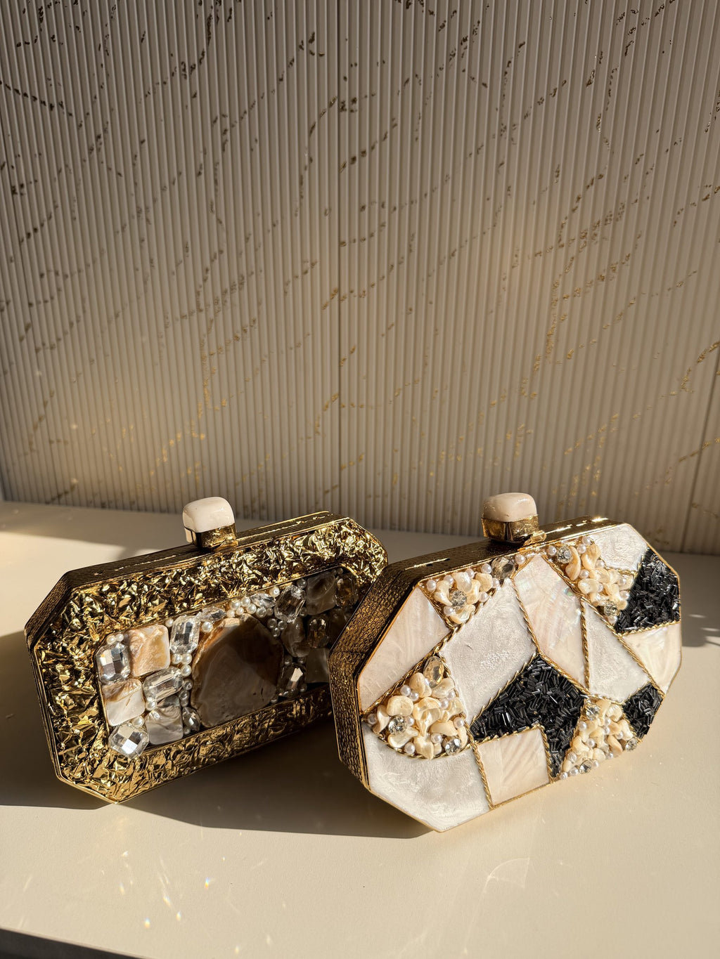 Close-up of the bottom hinges of the Gilded Muse brass clutch, highlighting durable construction.