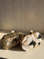 Close-up of the bottom hinges of the Gilded Muse brass clutch, highlighting durable construction.