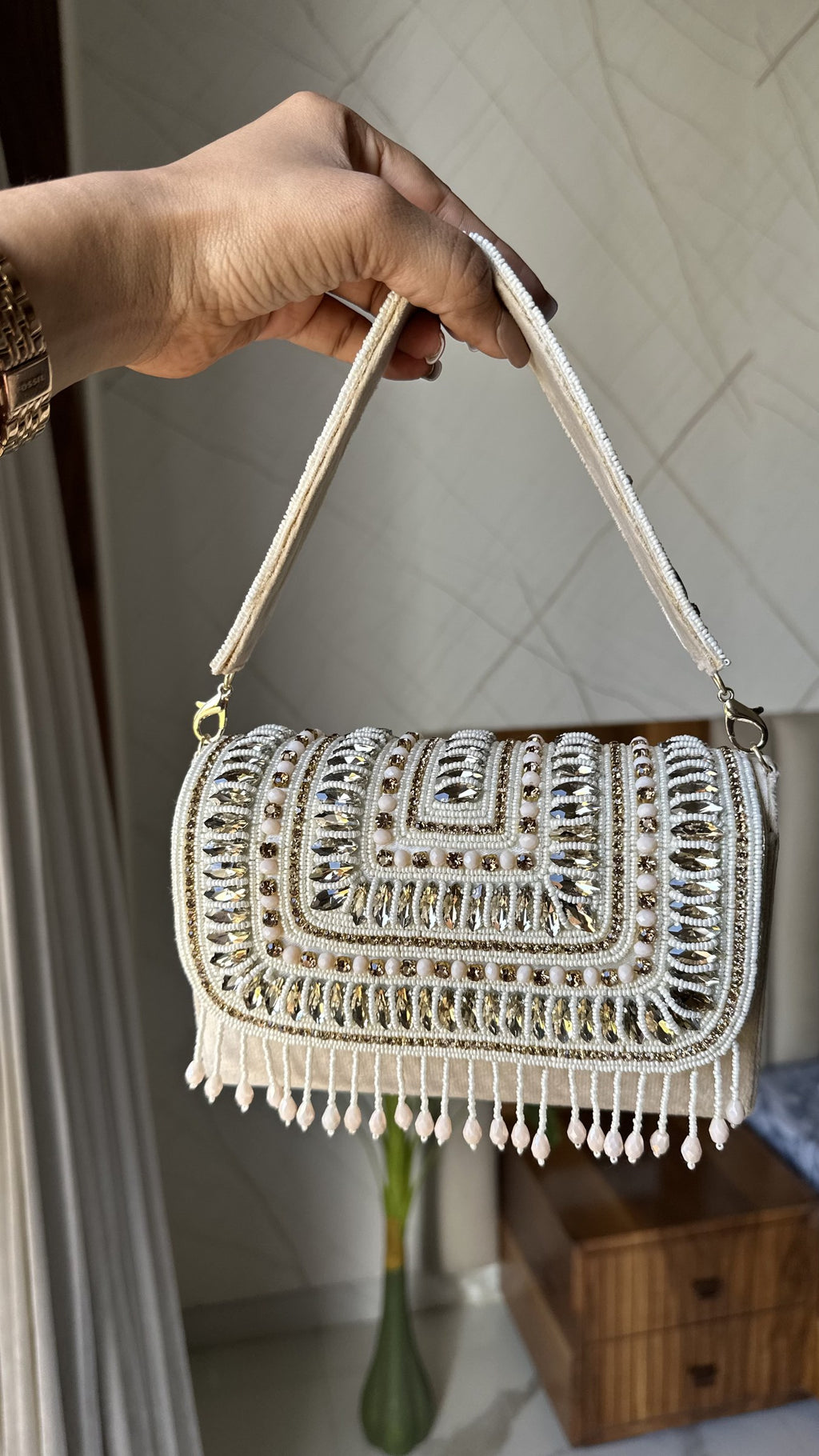 The Glimmer Grip clutch held handheld, highlighting its light-reflecting shine.