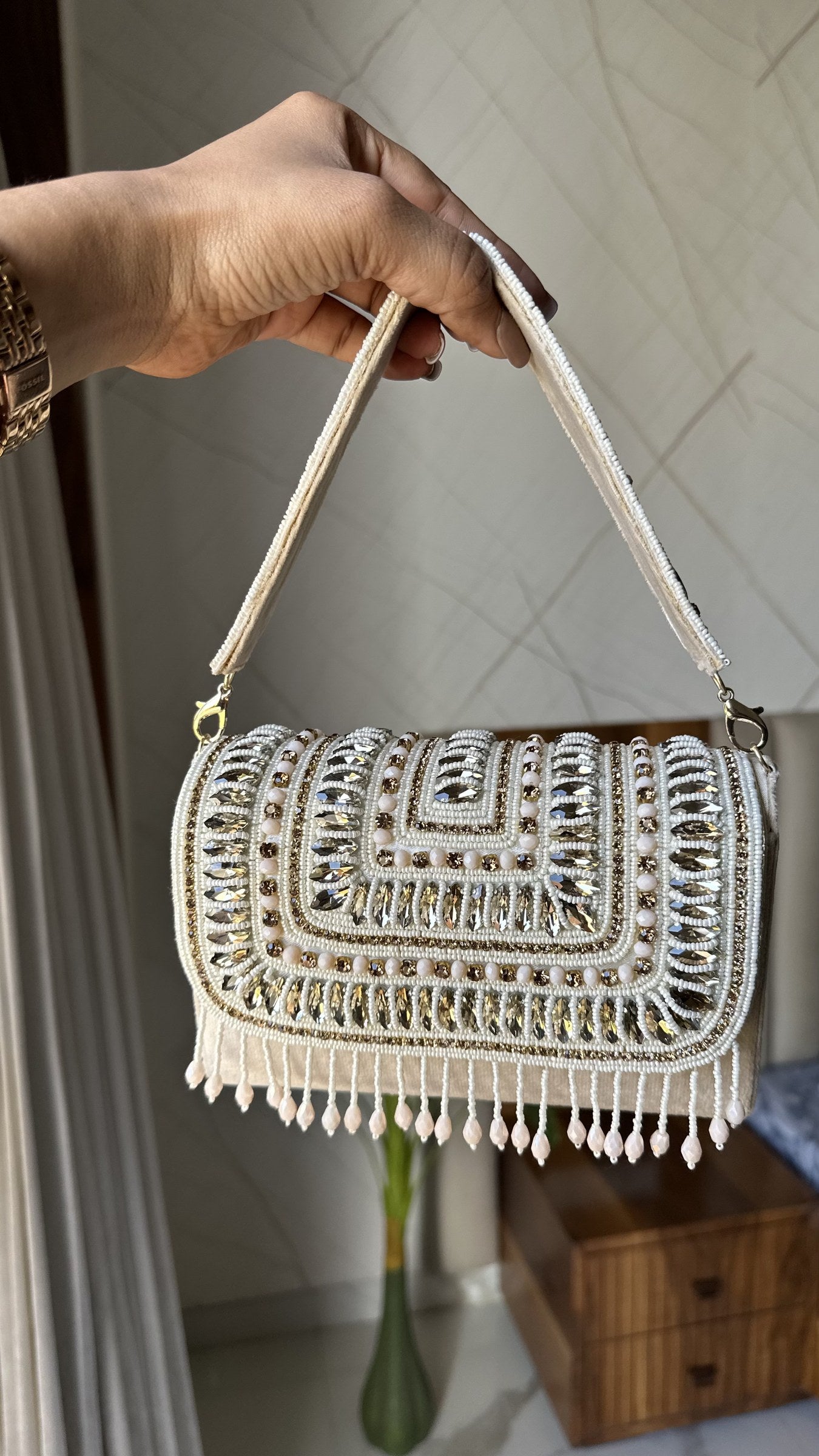 The Glimmer Grip clutch held handheld, highlighting its light-reflecting shine.
