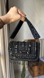 Lifestyle layout of the Glimmer Grip clutch next to evening coordinates and champagne.