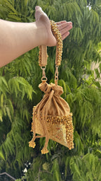 Handheld view of the Jhankar Potli demonstrating its wristlet drape and size proportion.