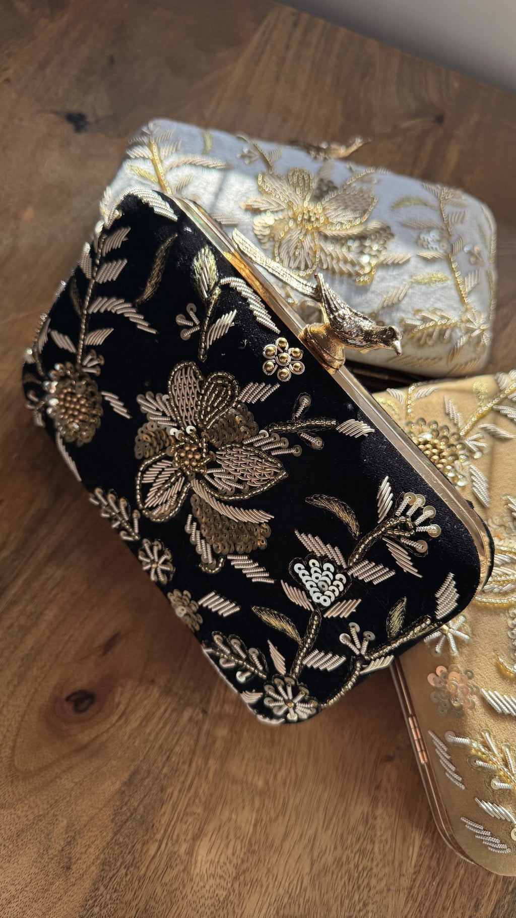 Kashi velvet clutch displaying its gold threadwork embroidery and signature brass peacock knob.
