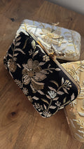 Kashi velvet clutch displaying its gold threadwork embroidery and signature brass peacock knob.