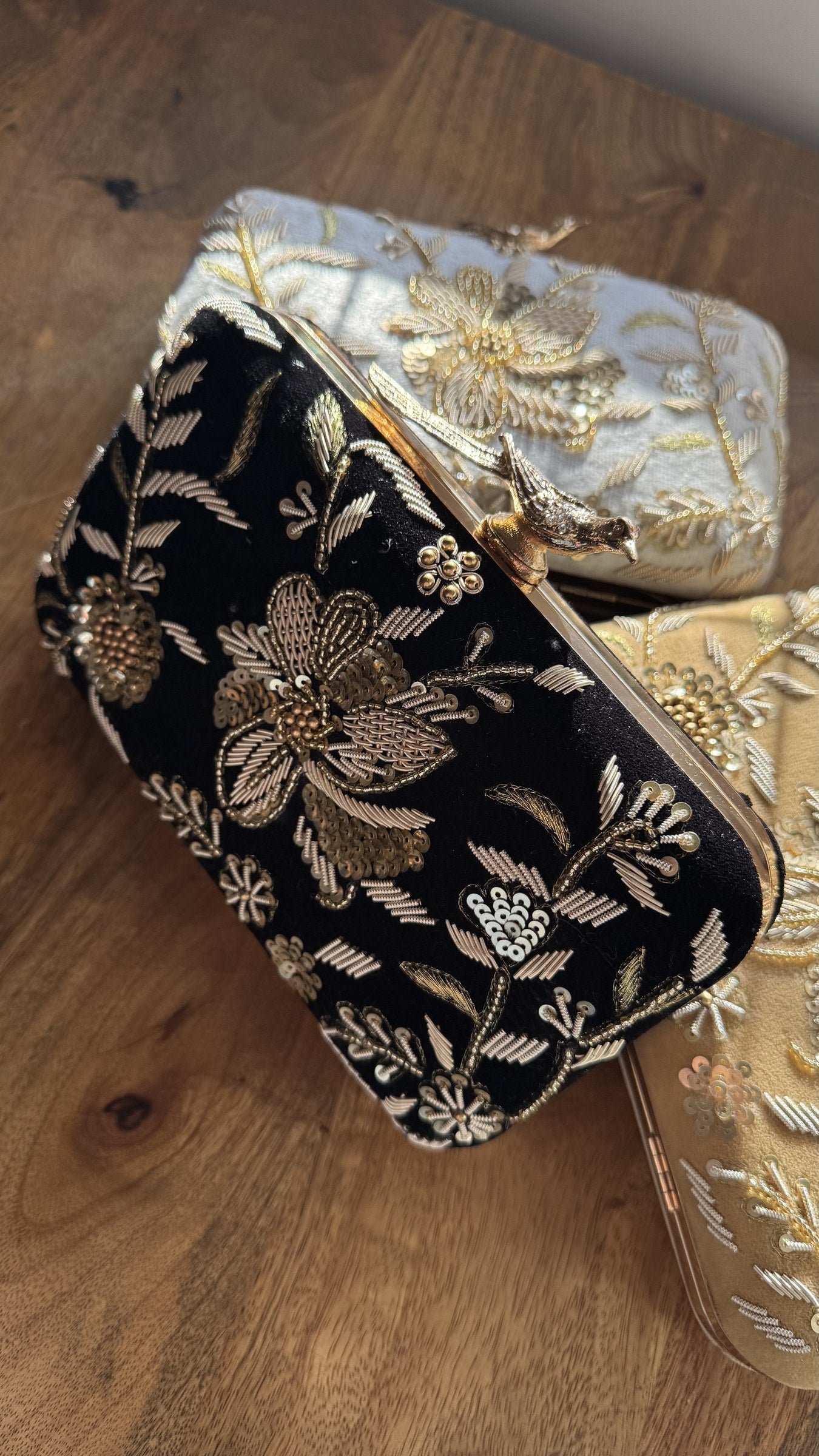 Kashi velvet clutch displaying its gold threadwork embroidery and signature brass peacock knob.