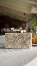 Kiara clutch displaying its metallic shimmer and short gold-tone wrist handle.