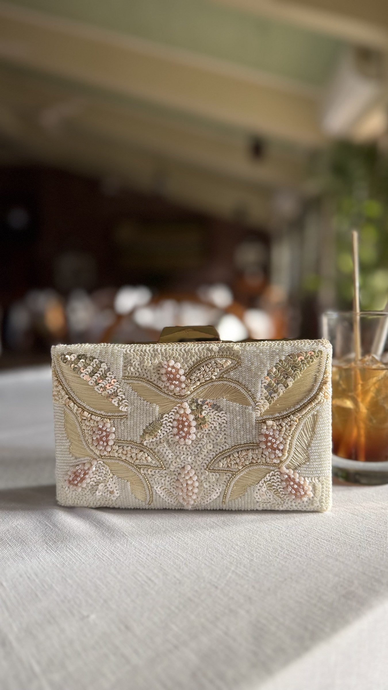 Kiara clutch displaying its metallic shimmer and short gold-tone wrist handle.