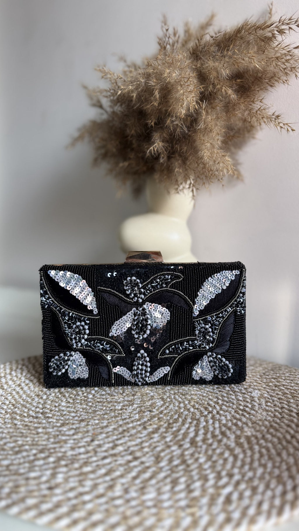 The Kiara clutch held by its wrist handle, illustrating wristlet carry style.