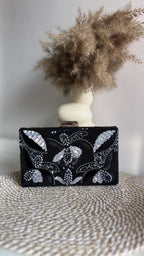 The Kiara clutch held by its wrist handle, illustrating wristlet carry style.