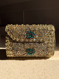 Kundan Peacock Heritage Clutch displaying its gold Kundan stones, green velvet, and brass peacock clasp.
