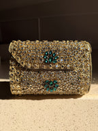 Kundan Peacock Heritage Clutch displaying its gold Kundan stones, green velvet, and brass peacock clasp.