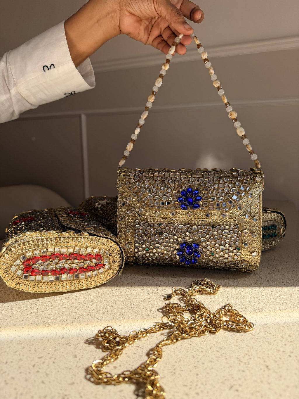 Flat lay of the Kundan clutch showing the gold-tone sling chain attached.