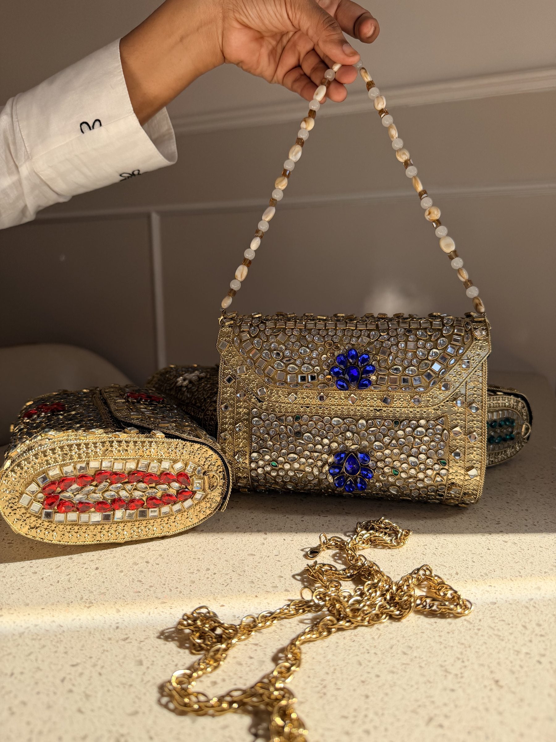 Flat lay of the Kundan clutch showing the gold-tone sling chain attached.