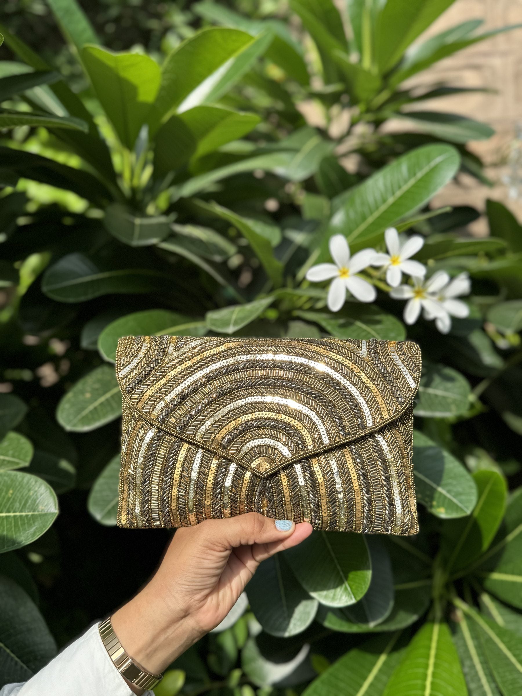 The Leher Waves bag held by its short beaded wrist strap, showing a sophisticated wristlet carry.