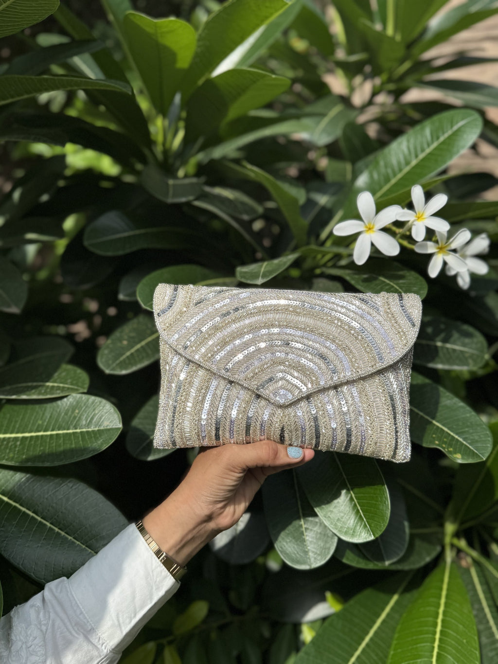Lifestyle layout of the Leher Waves flap bag next to traditional wedding attire and jewelry coordinates.