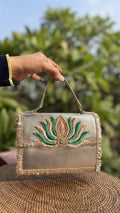Lotus Treasure evening clutch in gold, displaying its sculpted lotus front panel and chain.