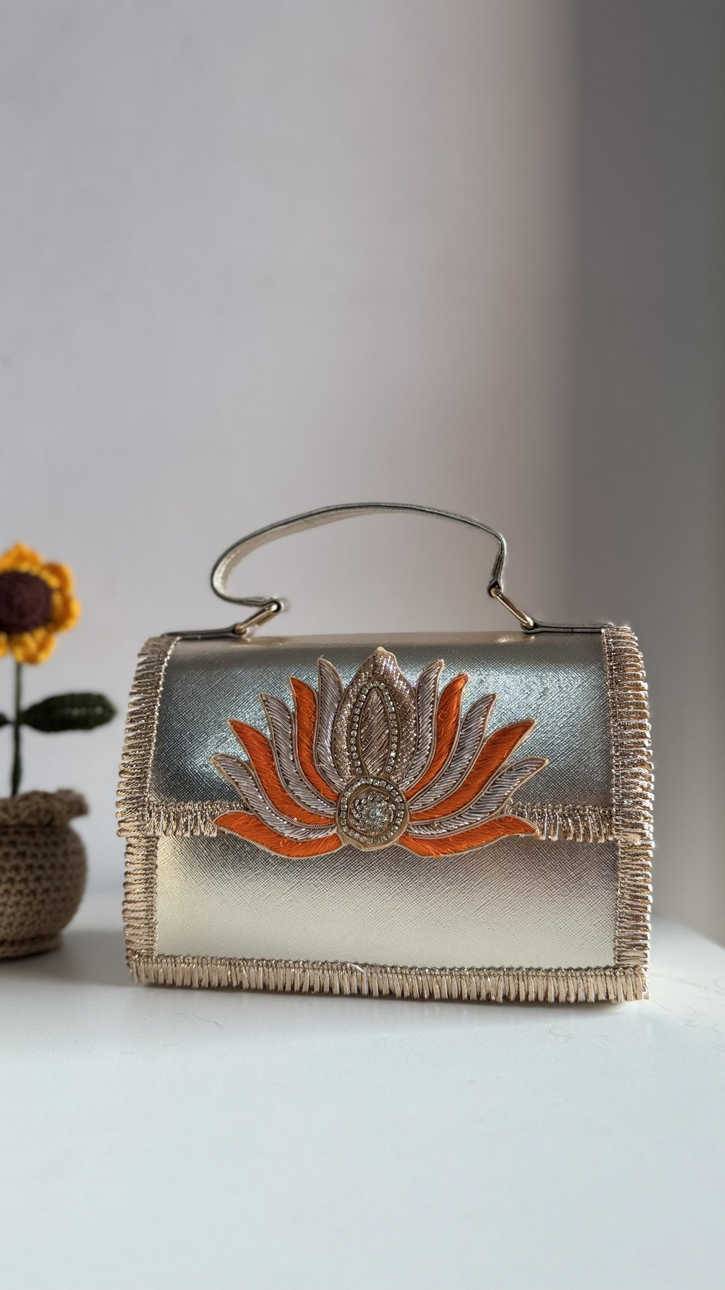The Lotus Treasure clutch held handheld, illustrating its classic evening proportions.