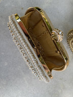 Flat lay of the Luxe Grip clutch next to matching gold sandals and pearl jewelry.