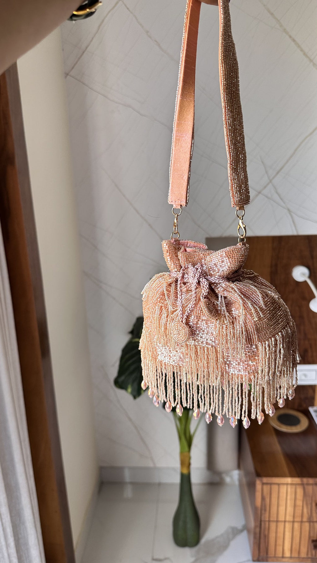 The Majestyy Potli held by a model, showcasing its elegant proportion and wristlet drape.