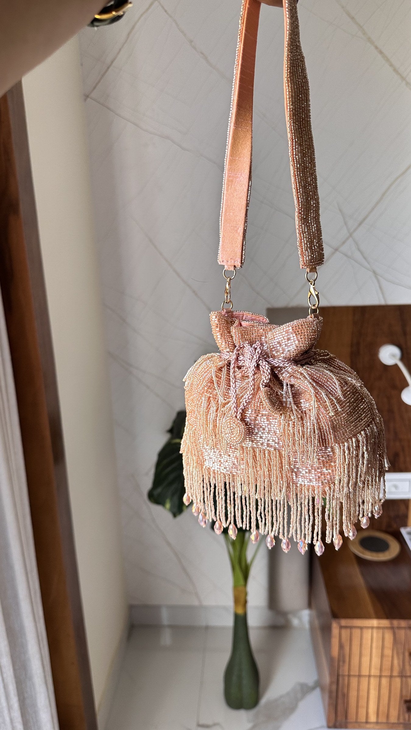 The Majestyy Potli held by a model, showcasing its elegant proportion and wristlet drape.