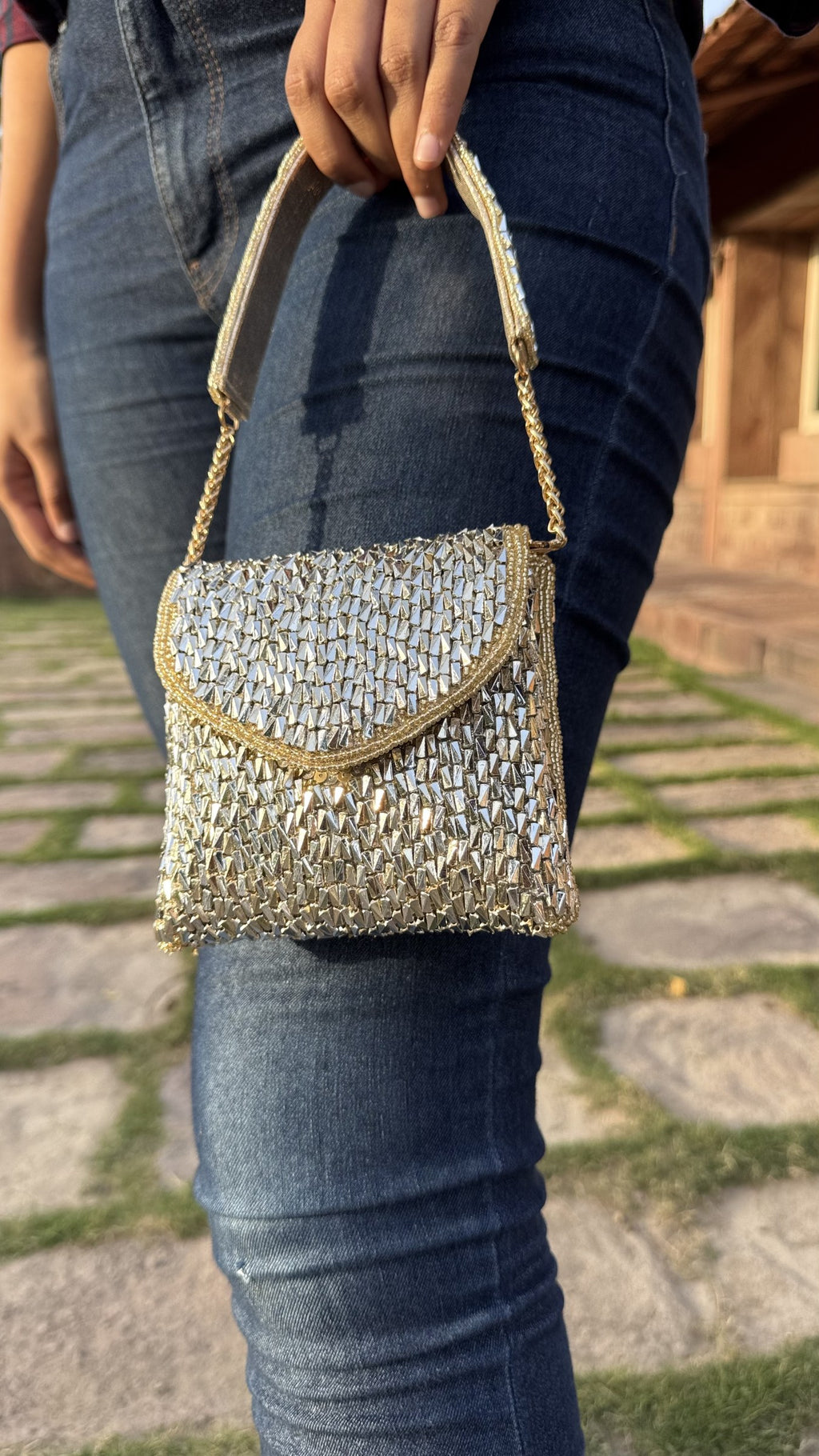 Lifestyle layout of the Mini Saanjh mixed-metal clutch next to gold and silver bangles.