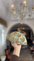 Side profile of the Mint Muse clutch showing its brass hinge and polished metal edge.