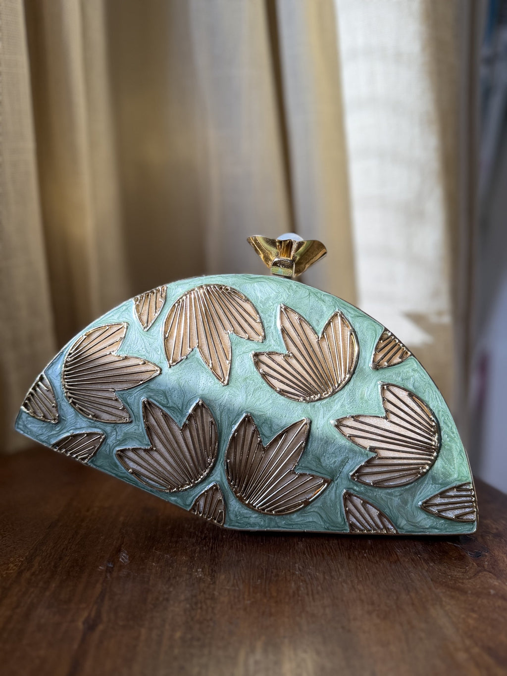 Lifestyle shot of the Mint Muse clutch styled handheld next to pastel coordinates and jewelry.