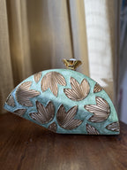 Lifestyle shot of the Mint Muse clutch styled handheld next to pastel coordinates and jewelry.