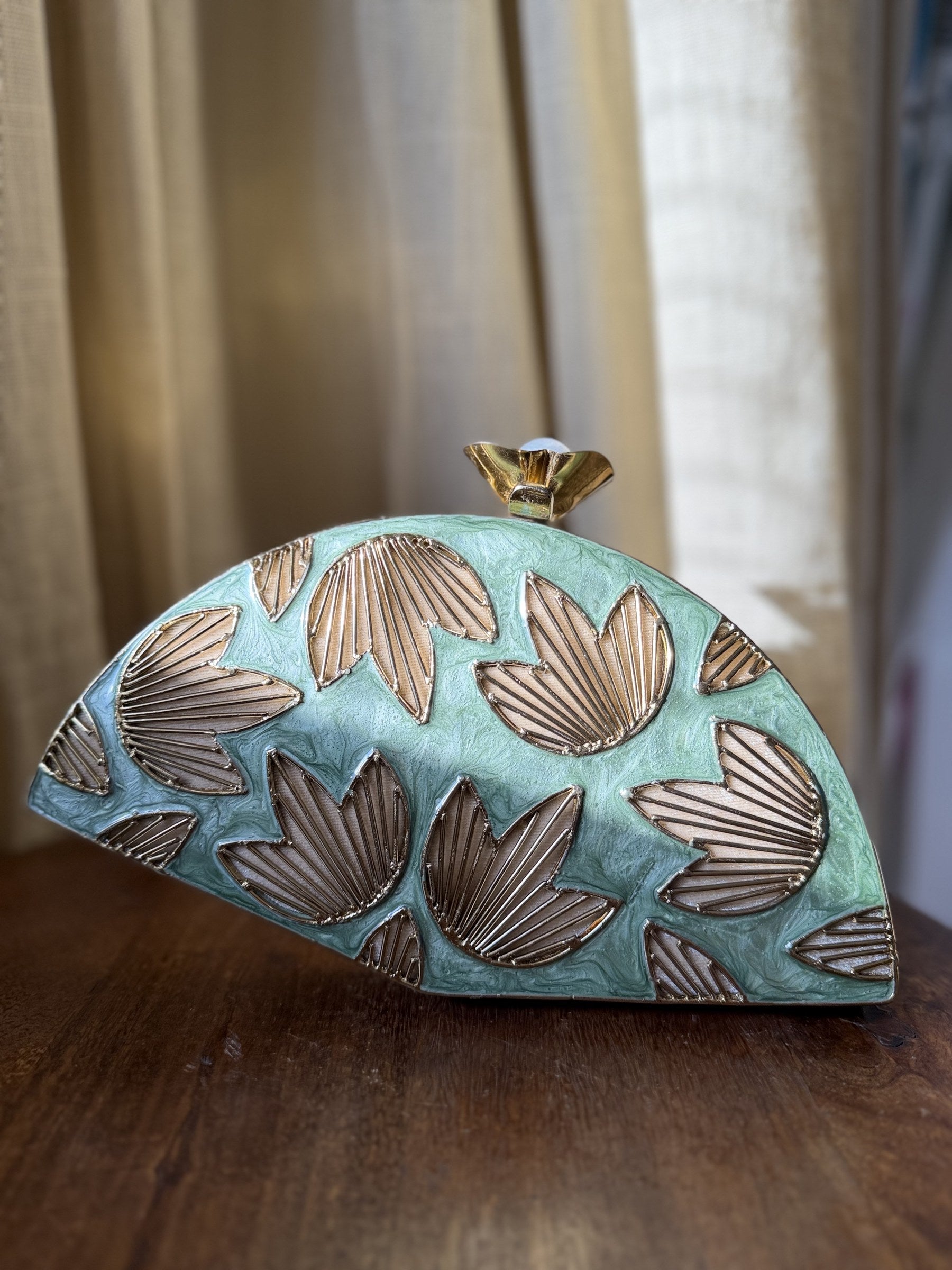 Lifestyle shot of the Mint Muse clutch styled handheld next to pastel coordinates and jewelry.